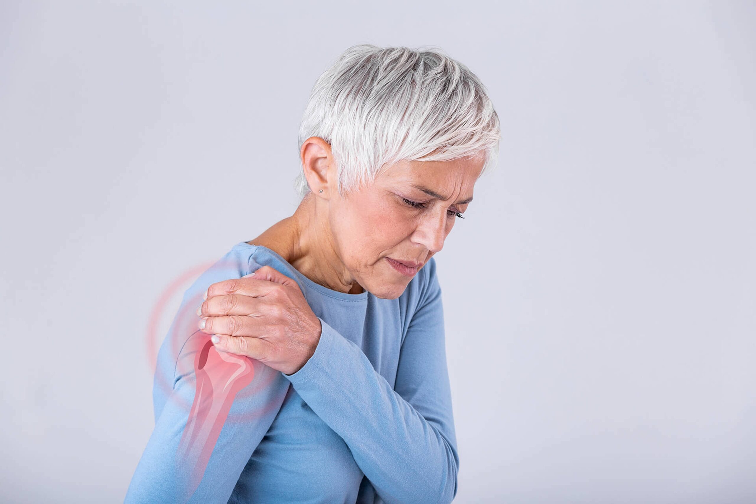 Senior woman in a blue shirt holds her aching shoulder. Shoulder dislocations and often accompanying labral tears are conditions Dr. Goradia of G2 Orthopedics treats everyday. Get relief - schedule your visit today!