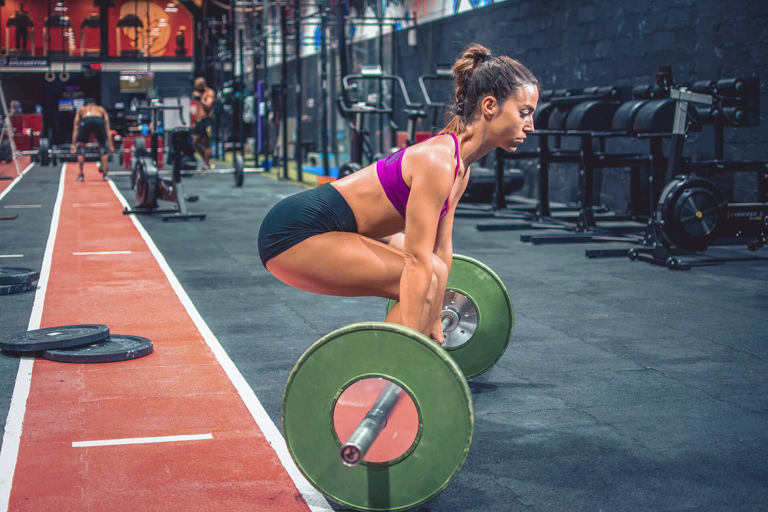 Young woman bends down to lift heavy weights. Don't let a shoulder dislocation or other injury stop you from the activities you love, from weight lifting, to playing ball, or anything in between.